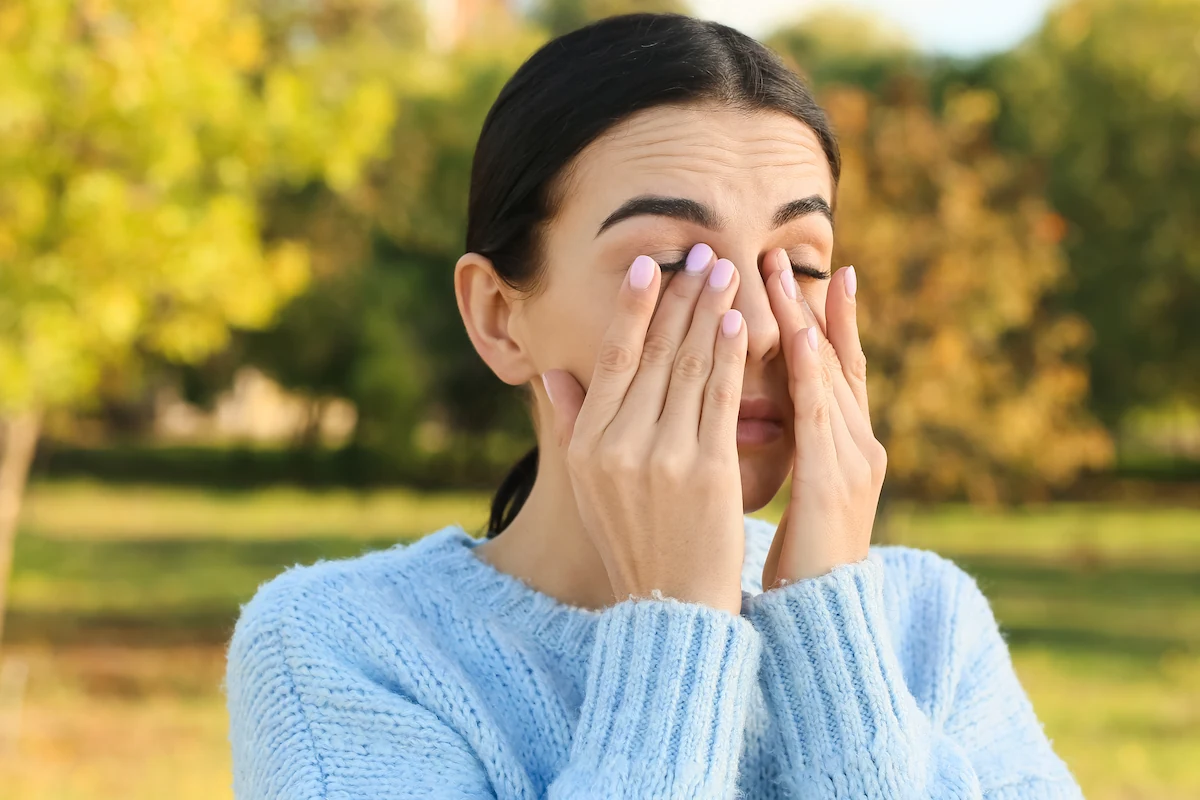 young woman rubbing eyes outdoors